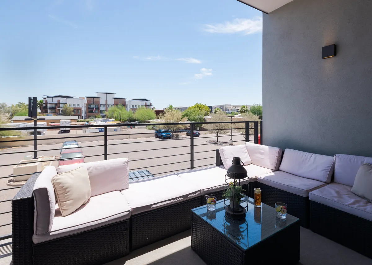This image showcases an outdoor seating area with a coffee table and a view of the surrounding urban environment. The area is bathed in natural morning light, suggesting a perfect spot for enjoying coffee or working outside. The setting captures the comfortable and relaxed atmosphere ideal for remote work breaks or casual socializing.