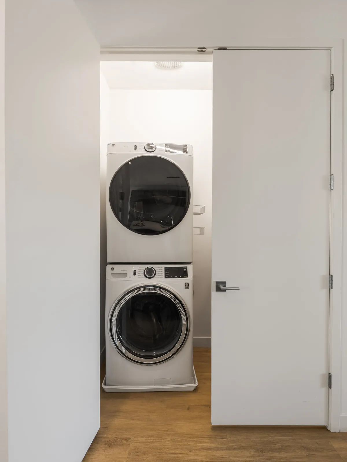 A compact interior utility space with a stacked washer and dryer, minimalist door design, and organized, functional layout.