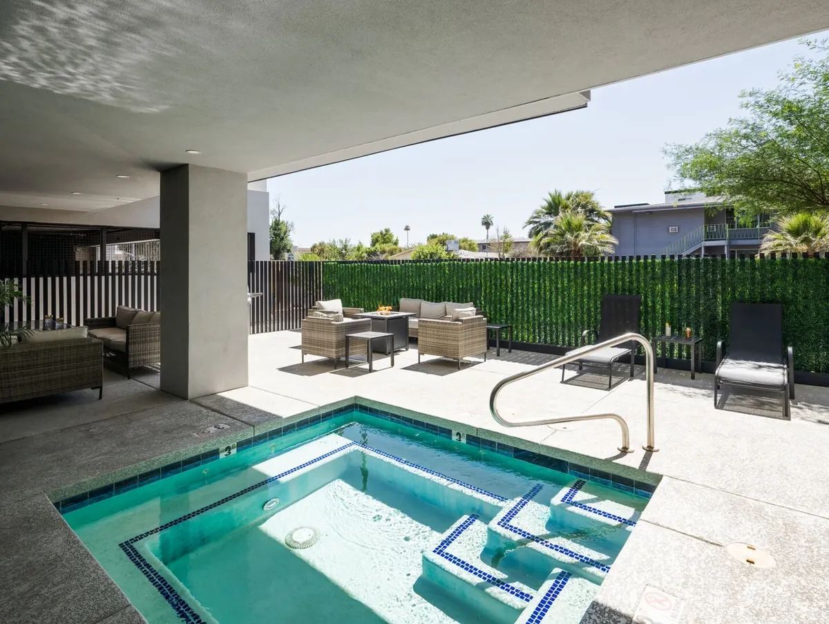 A tranquil spa pool area with inviting outdoor seating, surrounded by greenery. The serene setting features loungers and hints of sunset lighting, perfect for unwinding, socializing, or enjoying the outdoors—even if the hot tub is currently out of service.