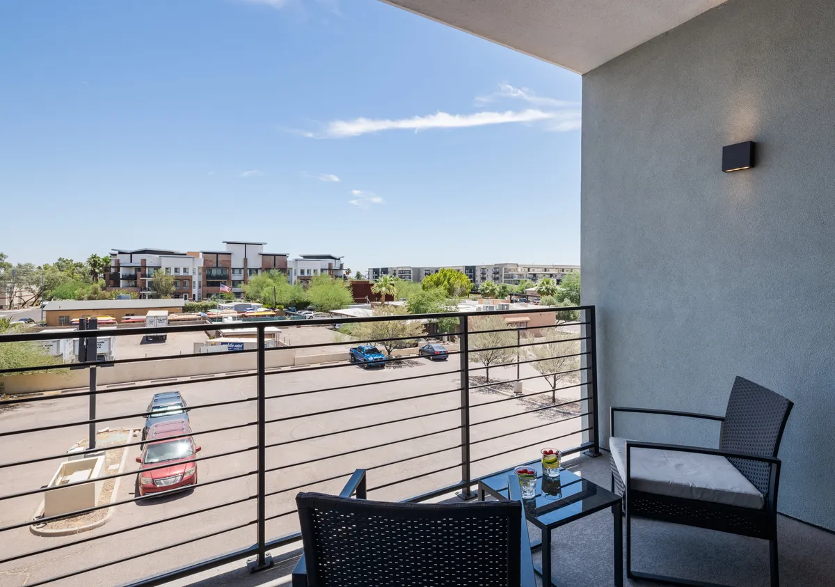 A private balcony with comfortable seating, a decorative plant on the table, and a tranquil view of the surrounding area. The space is ideal for sipping coffee at sunrise or enjoying a peaceful evening under the stars.