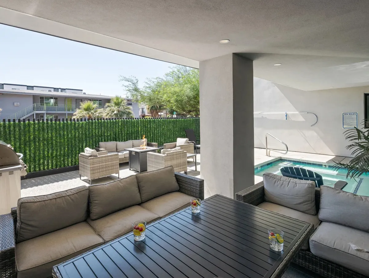 A serene outdoor common area with a swimming pool, lush greenery, ample seating, and a barbecue space. The setting is designed for relaxation and sociable gatherings, encapsulating the spirit of a resort-style retreat.