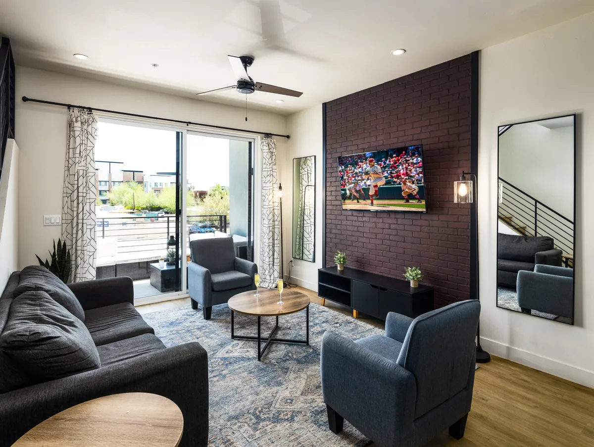 The hero image showcases a bright, inviting living room with a plush sofa, comfortable chairs, a stylish coffee table, and a large TV. Sunlight streams through the window, creating a cheerful ambiance perfect for gathering with friends or family. The space hints at social activities like watching sports, sharing laughs, or celebrating special occasions.